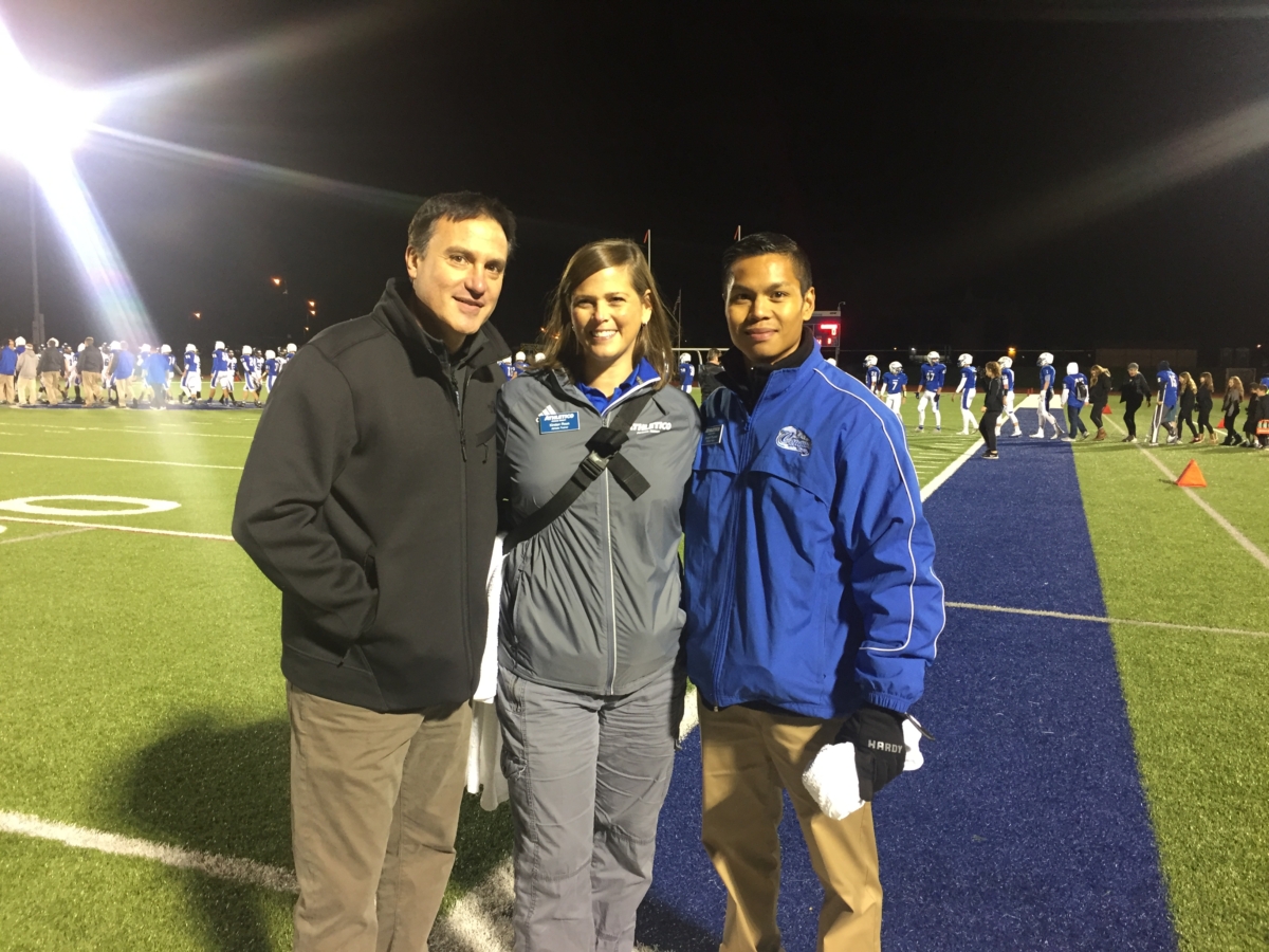 Joe Success Stories Photo Dr. Chams standing with man and woman on football field at night
