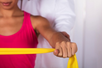 Woman with doctor performing shoulder surgery recovery exercise.